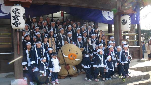 宗玄寺にて子ども義士行列の多数の参加者がまるいのを真ん中に記念撮影している写真